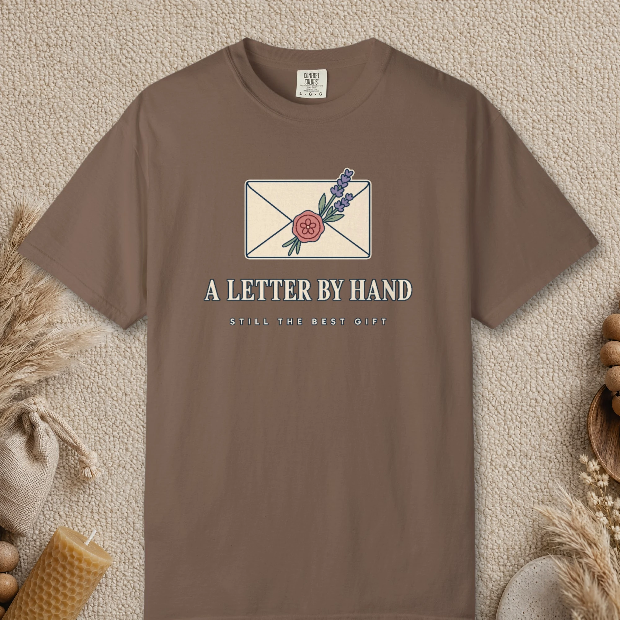 A Letter by Hand design on a Espresso Comfort Colors 1717 tee, laid flat