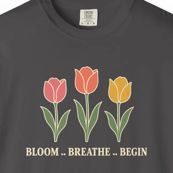 Close-up of the Bloom Breathe Begin print on a Graphite Comfort Colors 1717 tee