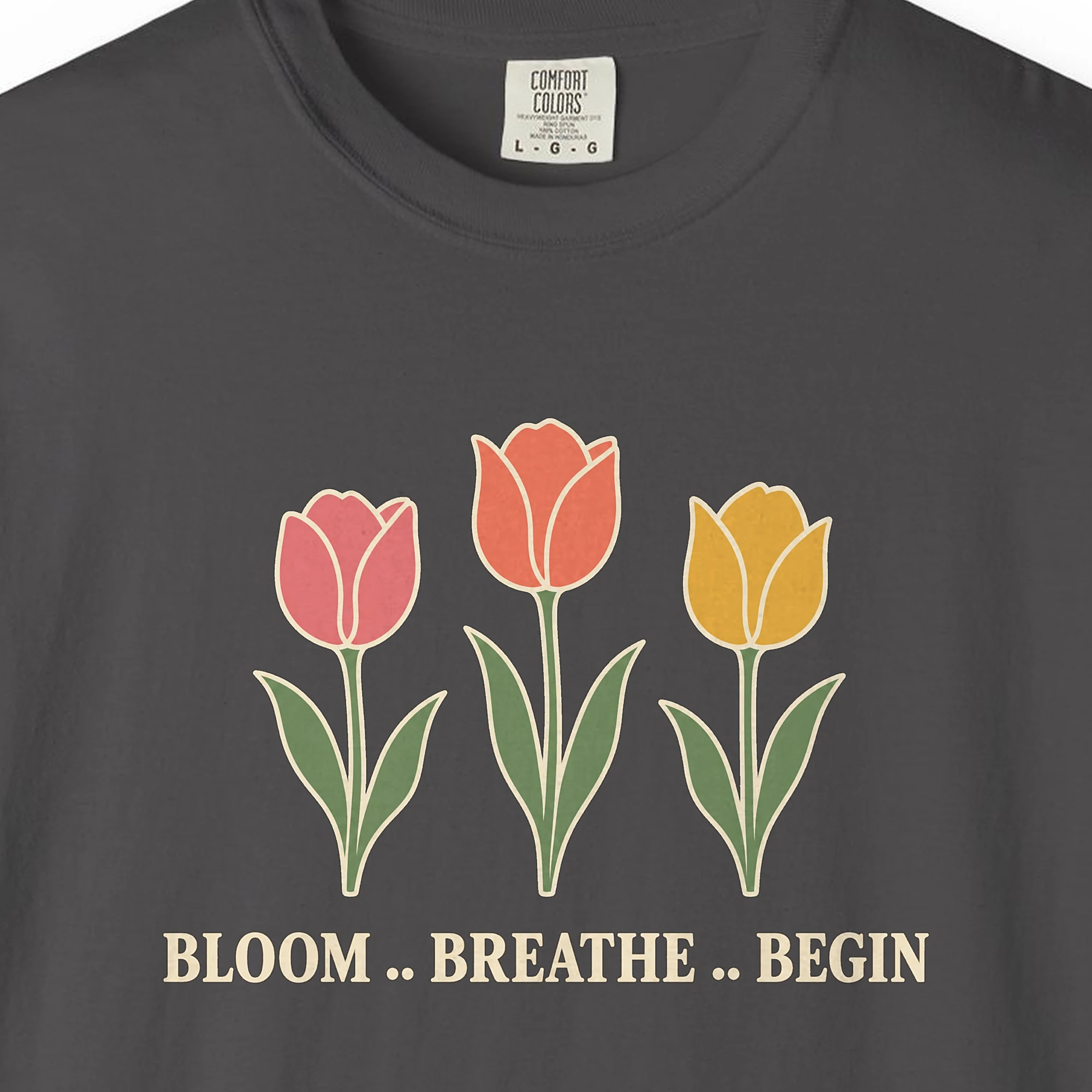 Close-up of the Bloom Breathe Begin print on a Graphite Comfort Colors 1717 tee