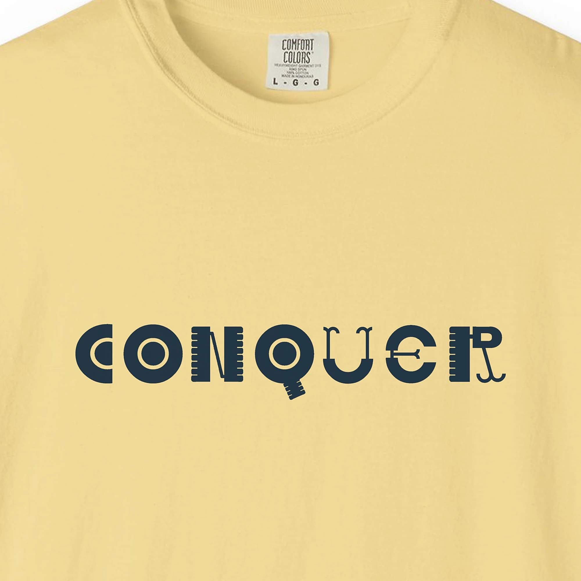 conquer-tee-butter-chest Close-up of the Conquer print on a Butter Comfort Colors 1717 tee