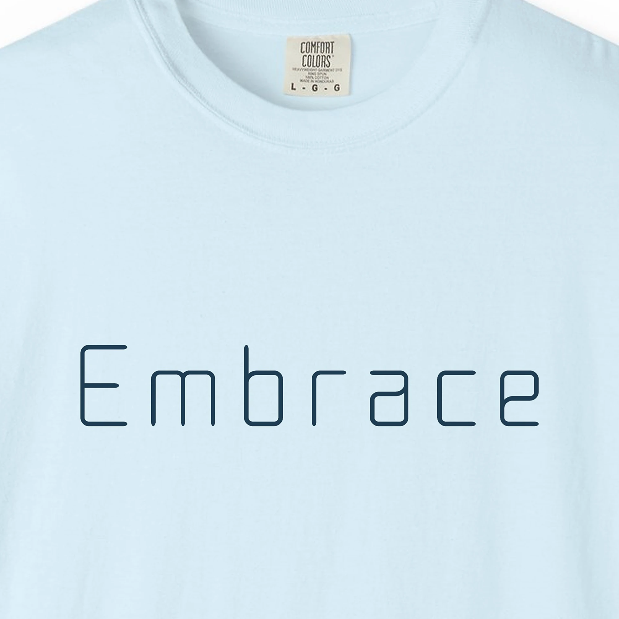 embrace-rounded-tee-chambray-chest Close-up of the Embrace Rounded print on a Chambray Comfort Colors 1717 tee