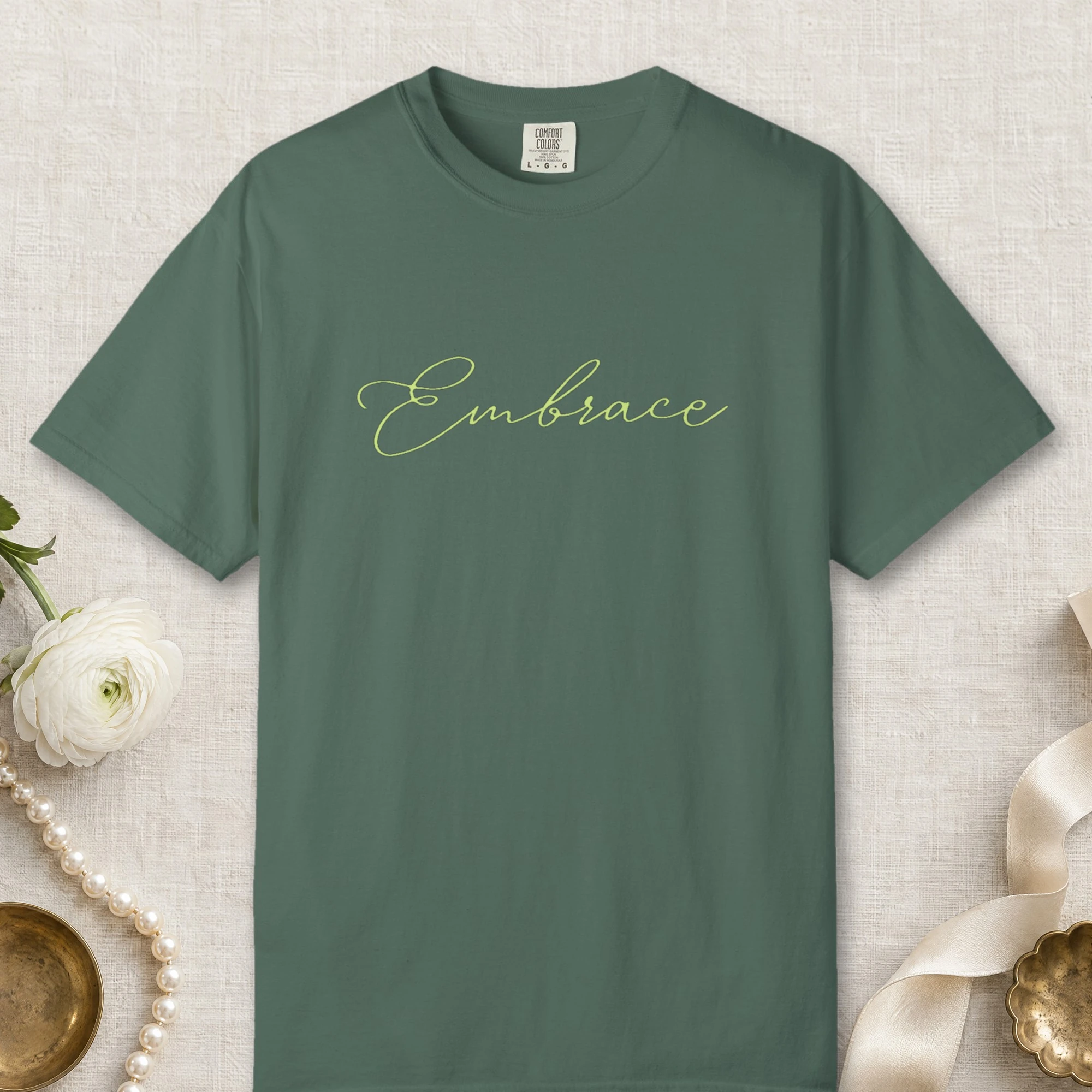 Embrace design on a Blue Spruce Comfort Colors 1717 tee, laid flat