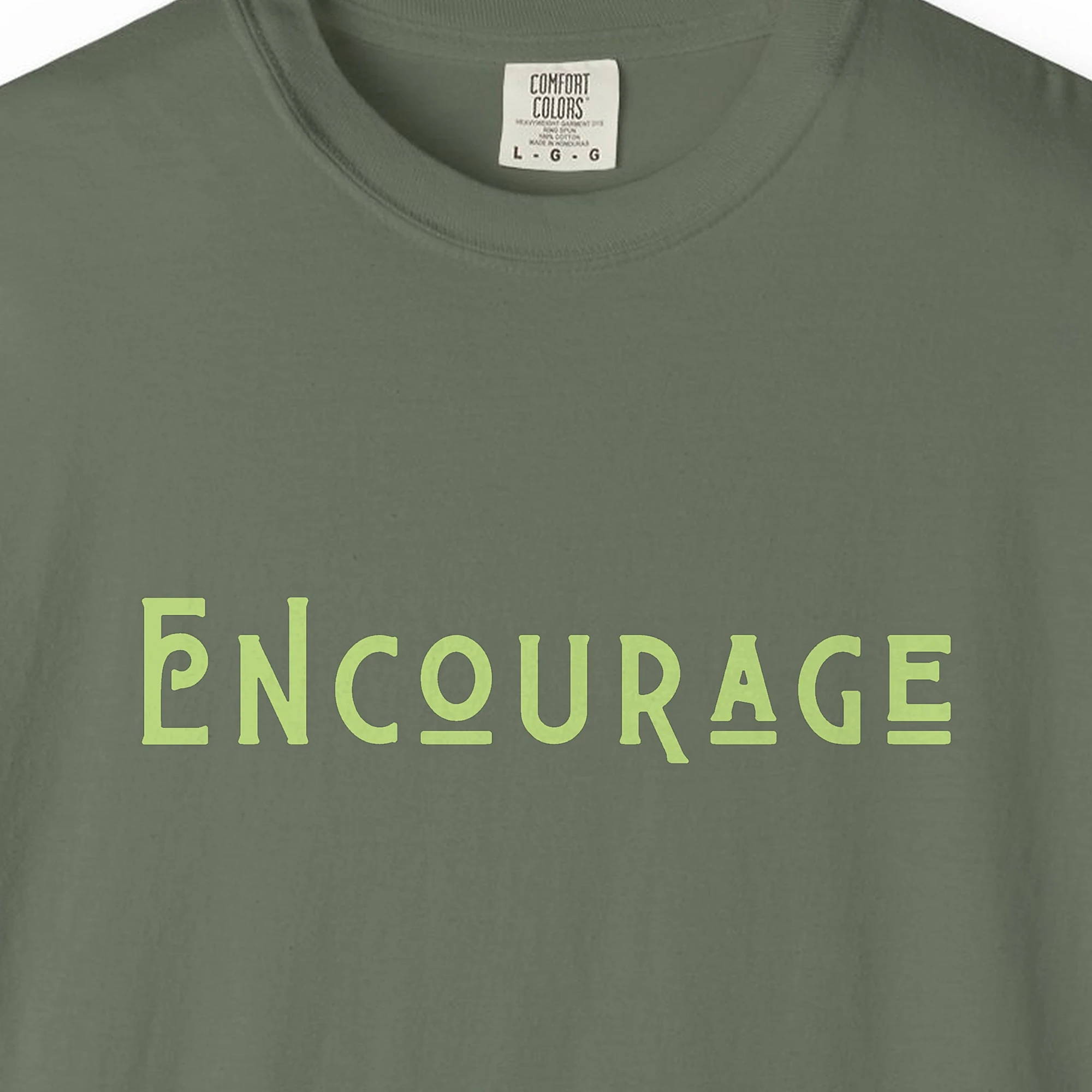 Close-up of the Encourage print on a Moss Comfort Colors 1717 tee