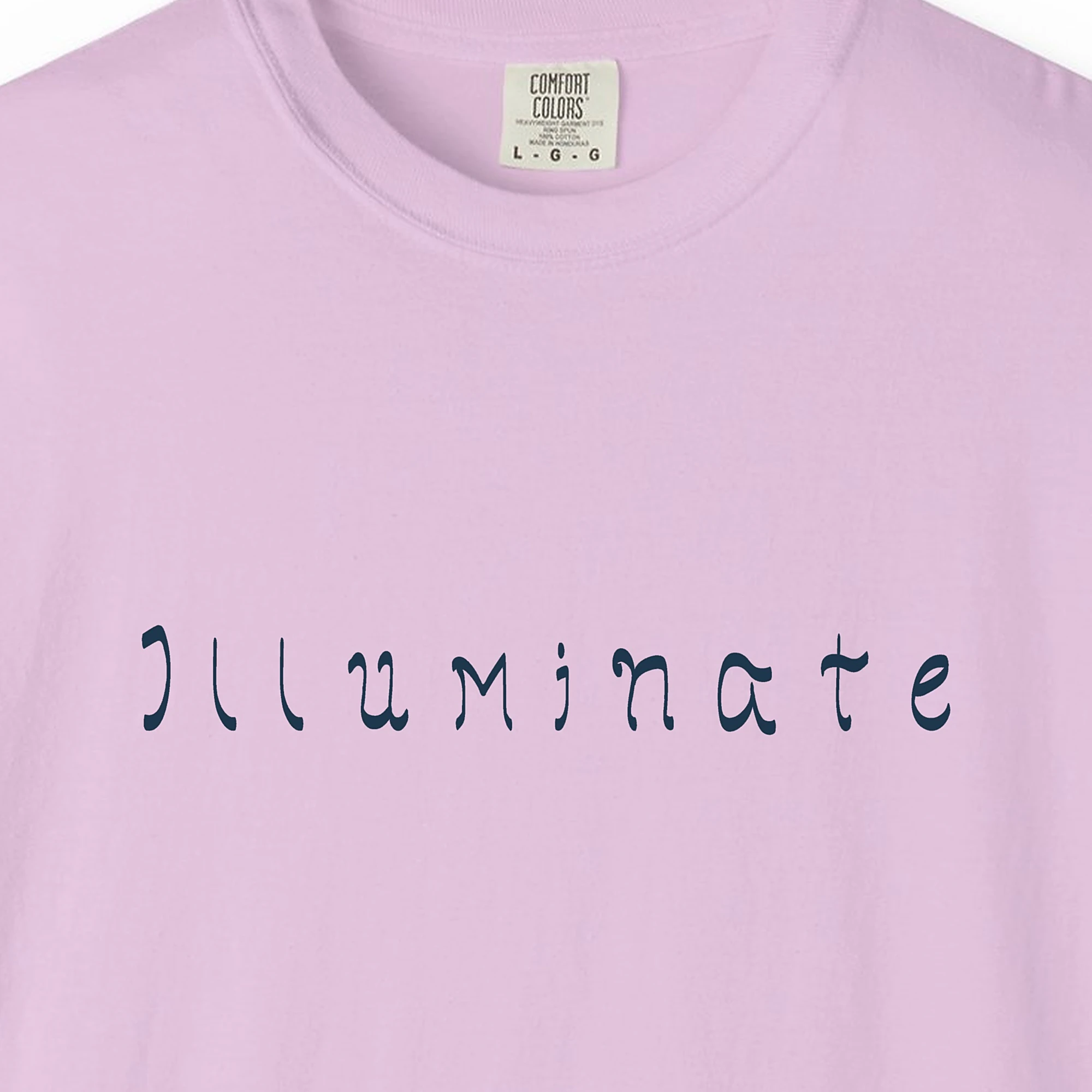 Close-up of the Illuminate Hand-Lettered print on a Orchid Comfort Colors 1717 tee