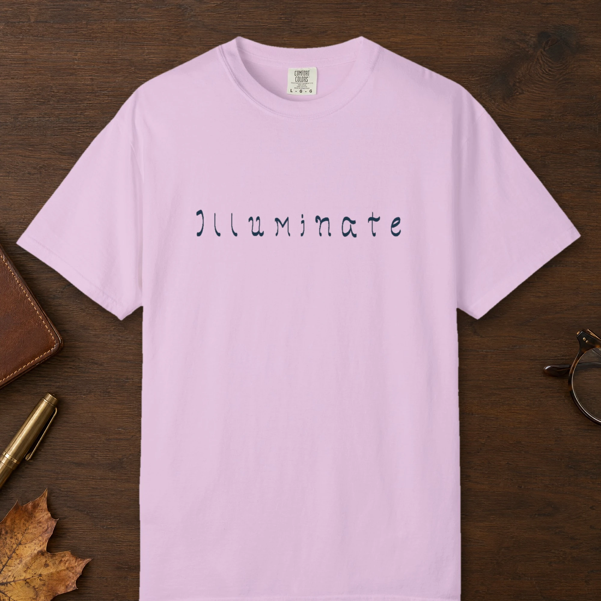 Illuminate Hand-Lettered design on a Orchid Comfort Colors 1717 tee, laid flat