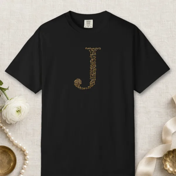 Initial J design on a Black Comfort Colors 1717 tee, laid flat