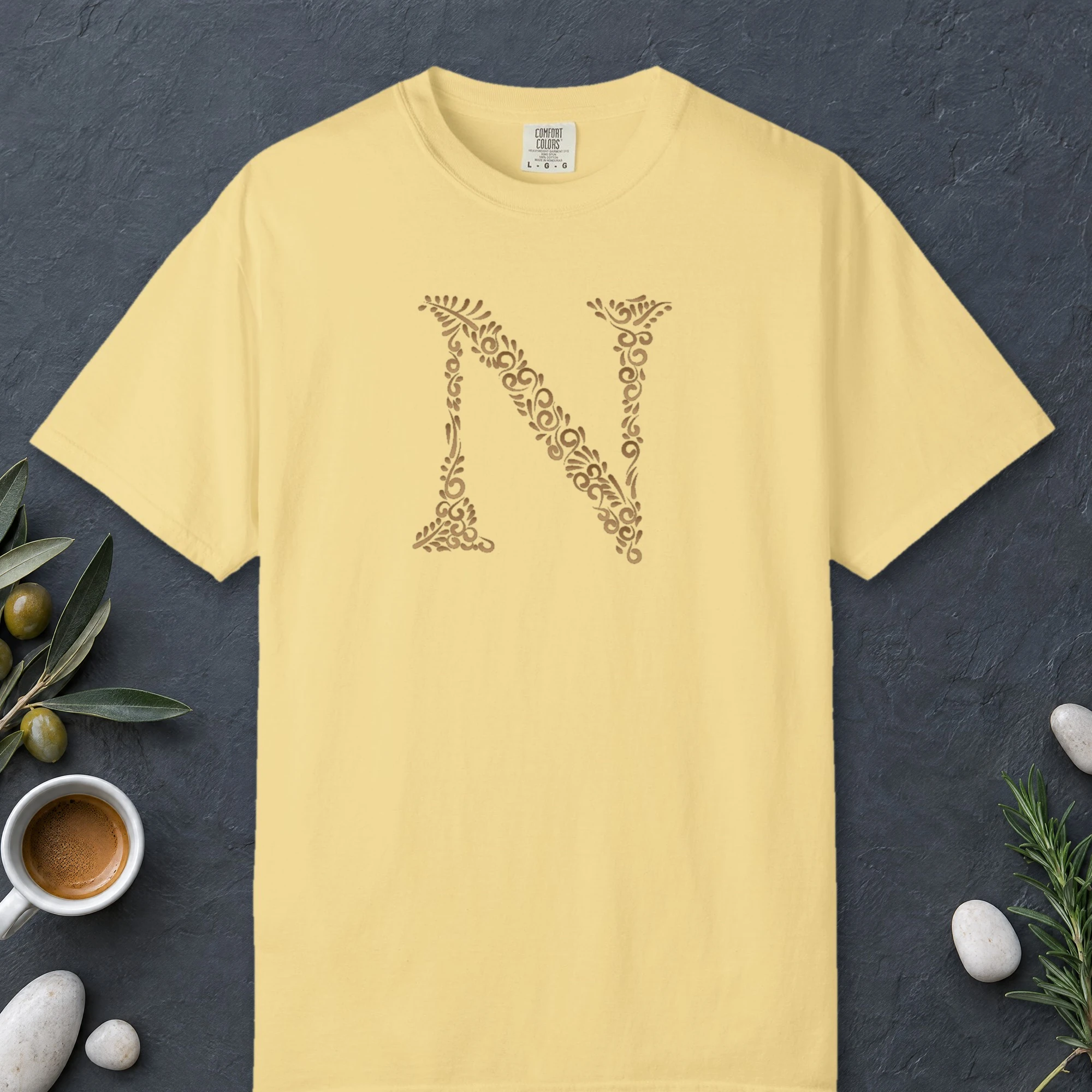 Initial N design on a Butter Comfort Colors 1717 tee, laid flat