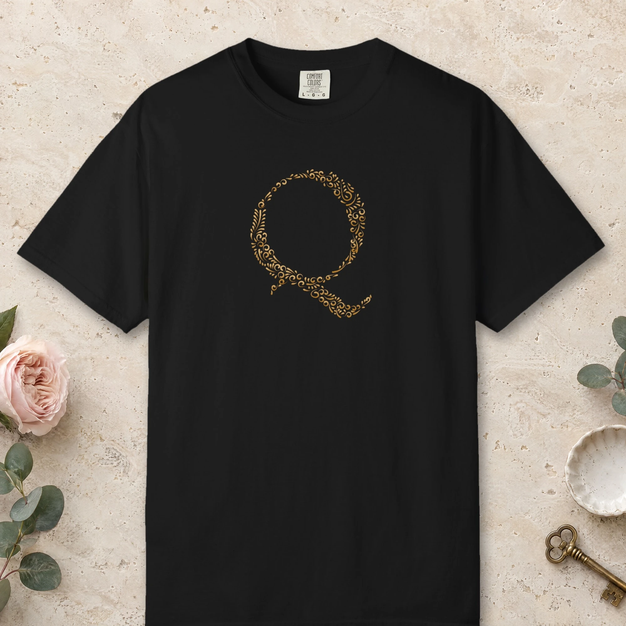 Initial Q design on a Black Comfort Colors 1717 tee, laid flat