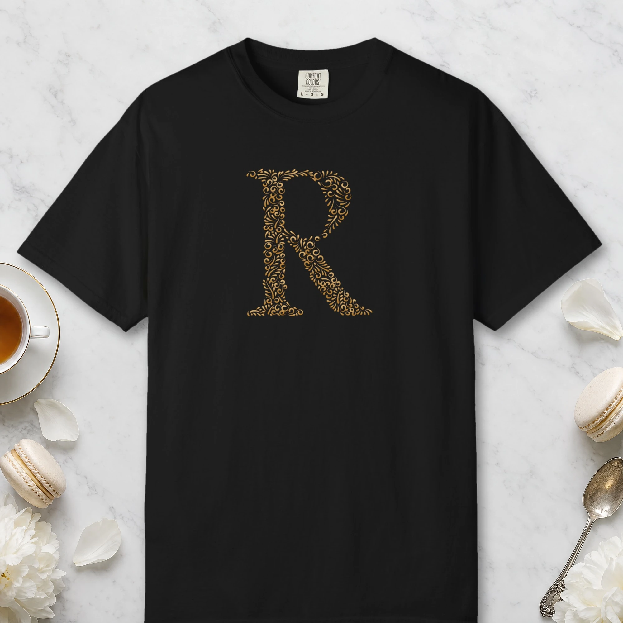Initial R design on a Black Comfort Colors 1717 tee, laid flat