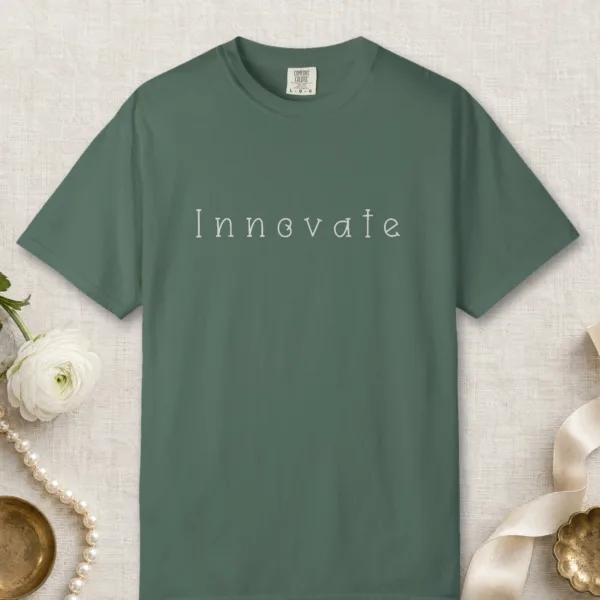 innovate-curled-serif-tee-blue-spruce-front Innovate Curled Serif design on a Blue Spruce Comfort Colors 1717 tee, laid flat