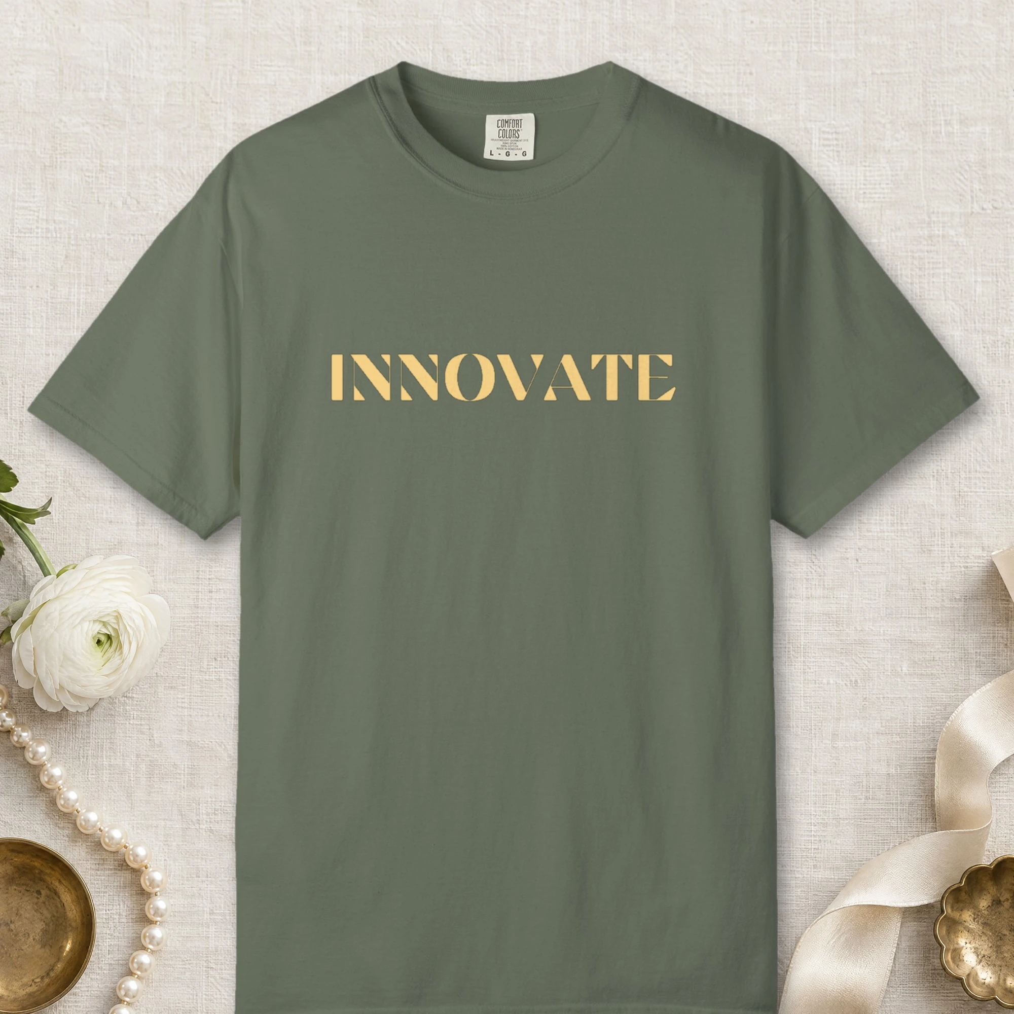 Innovate design on a Moss Comfort Colors 1717 tee, laid flat