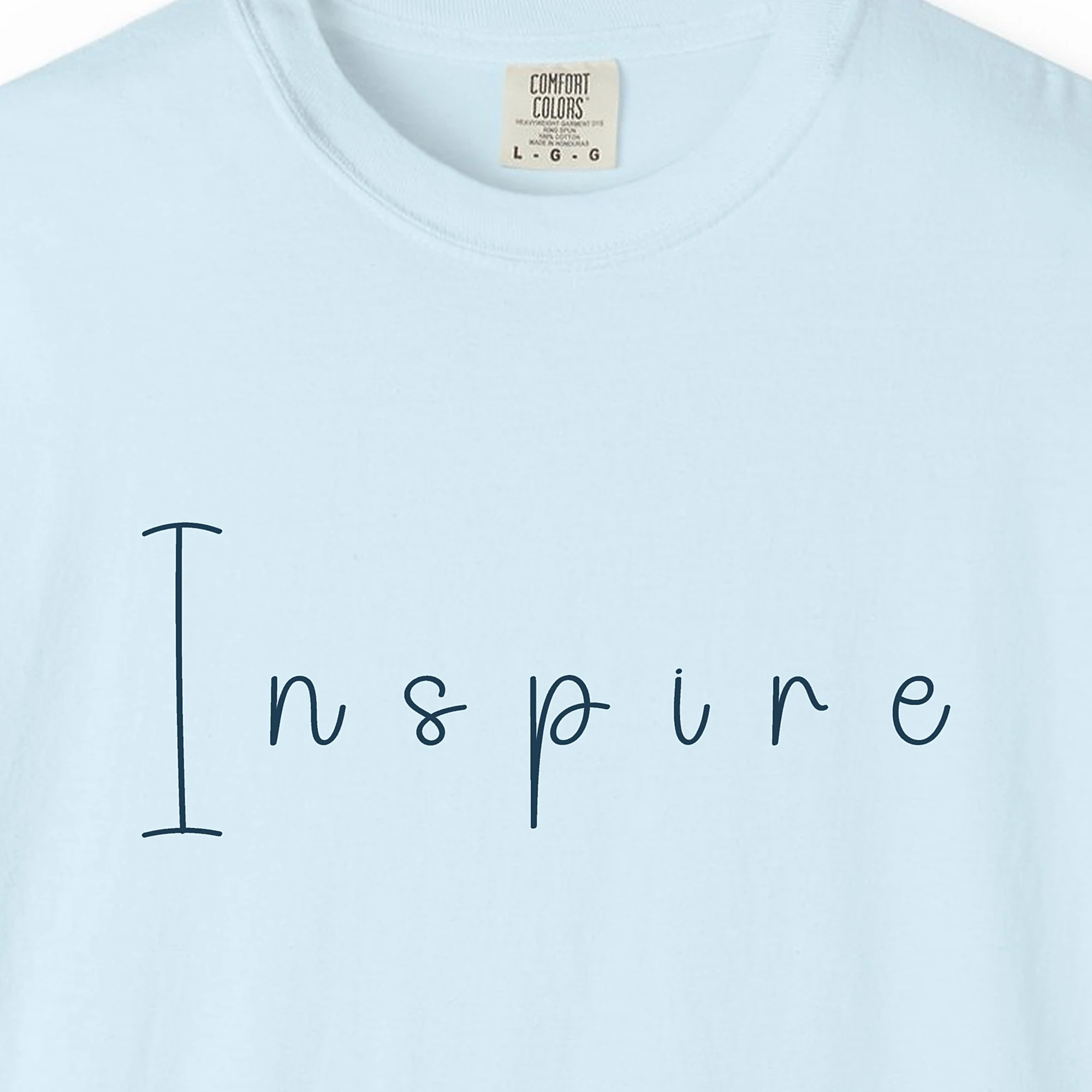 Close-up of the Inspire Hand-Drawn print on a Chambray Comfort Colors 1717 tee
