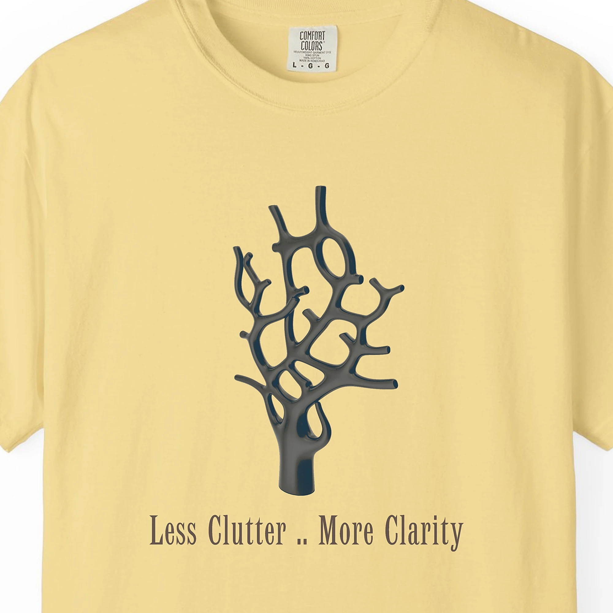 Close-up of the Less Clutter More Clarity print on a Butter Comfort Colors 1717 tee