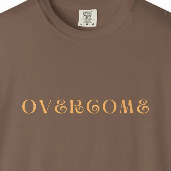 Close-up of the Overcome print on a Espresso Comfort Colors 1717 tee