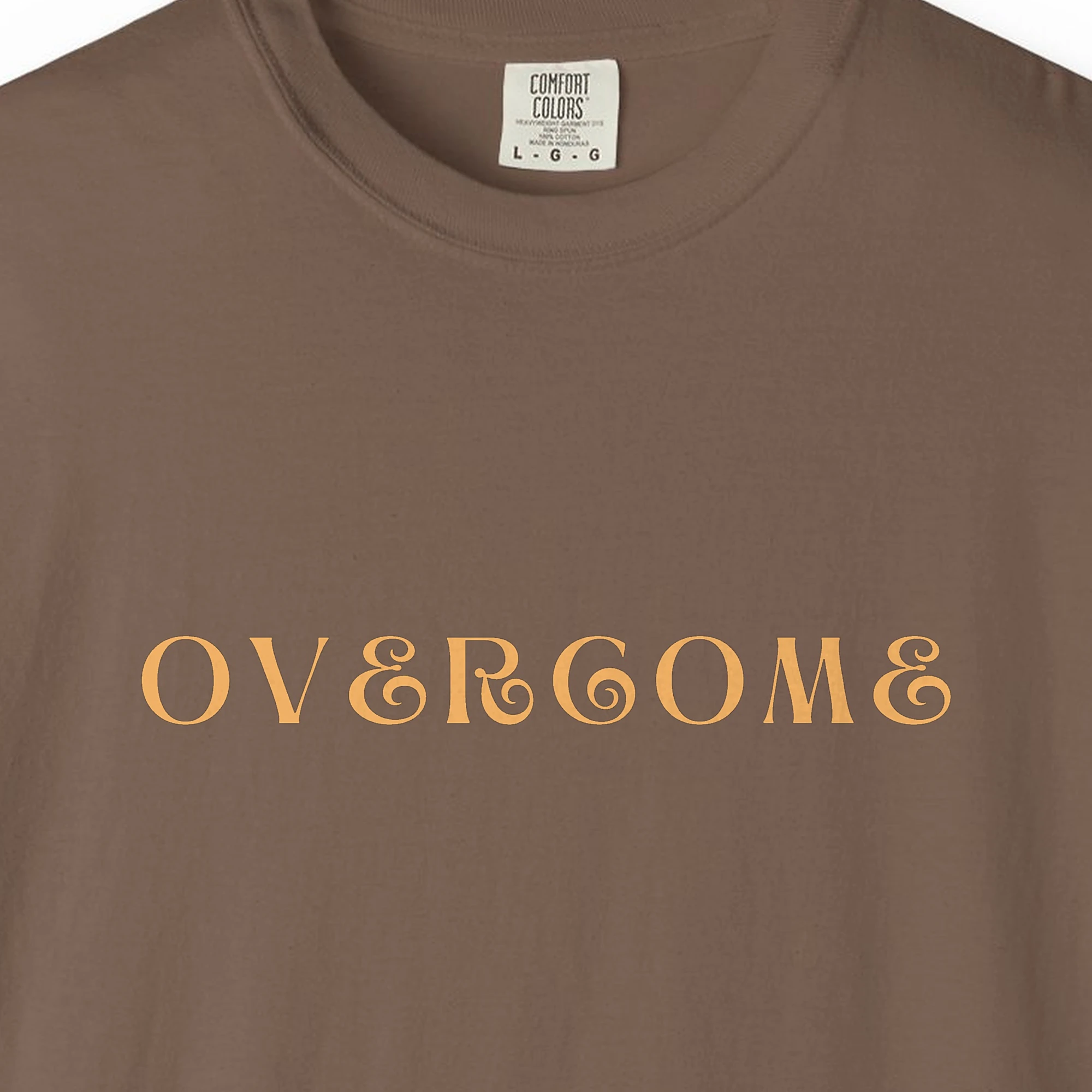 Close-up of the Overcome print on a Espresso Comfort Colors 1717 tee