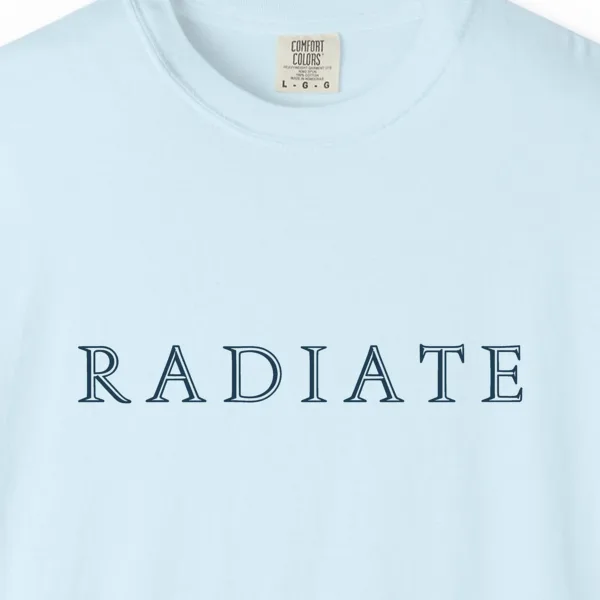 Close-up of the Radiate Inline Capitals print on a Chambray Comfort Colors 1717 tee