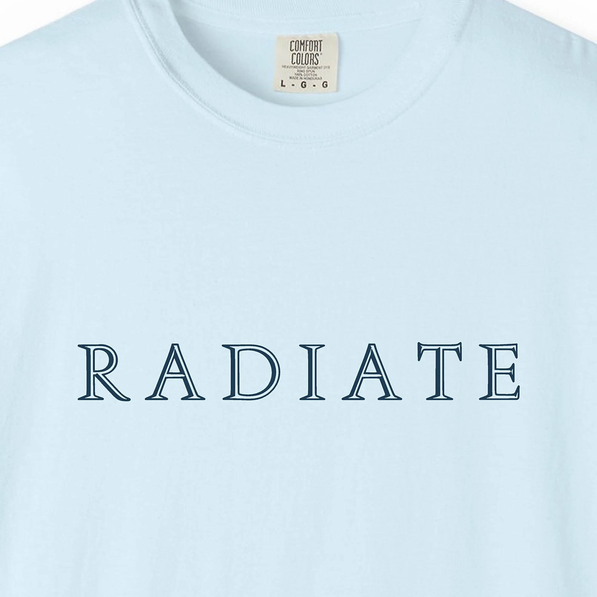 Close-up of the Radiate Inline Capitals print on a Chambray Comfort Colors 1717 tee