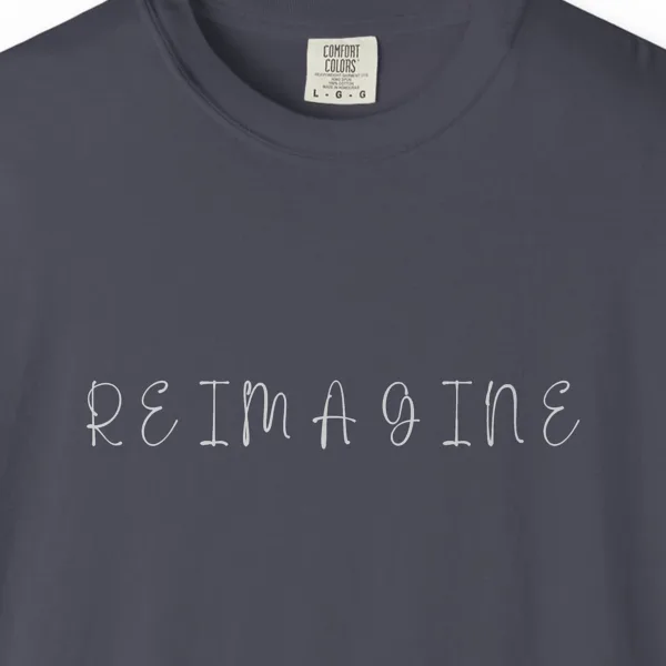 reimagine-handwritten-capitals-tee-navy-chest Close-up of the Reimagine Handwritten Capitals print on a Navy Comfort Colors 1717 tee