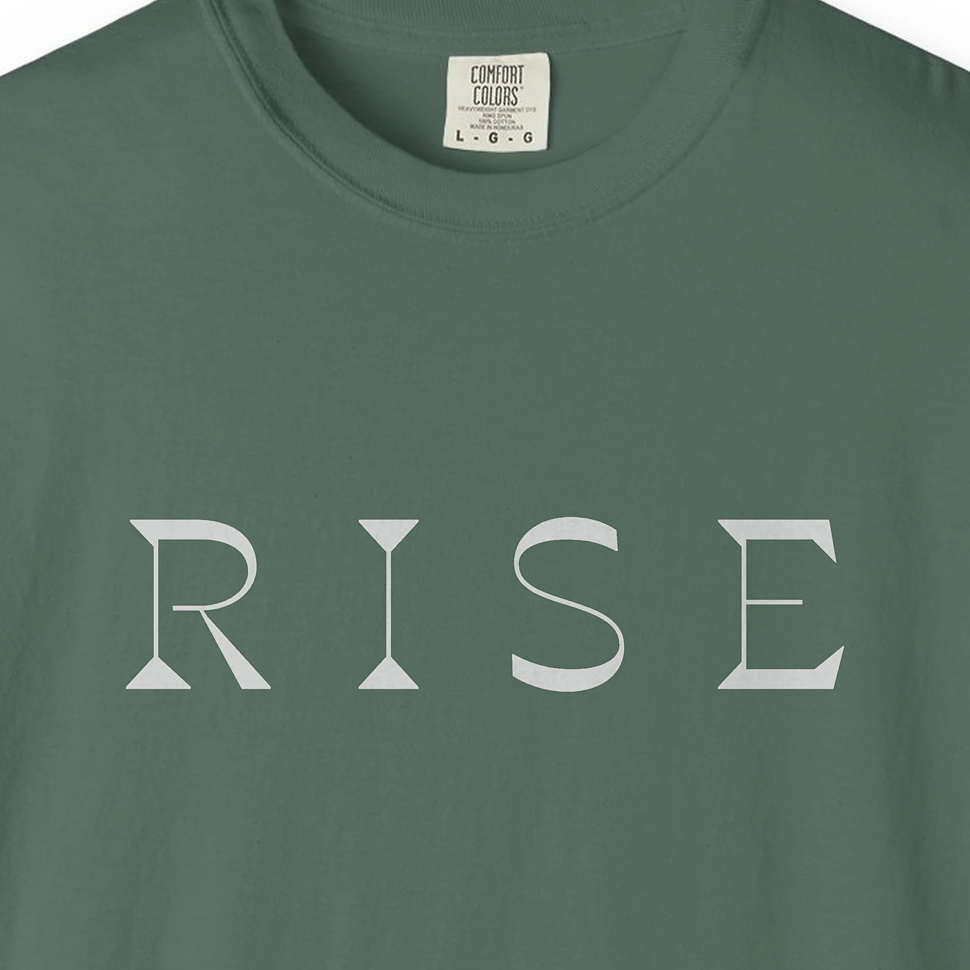 rise-bold-capitals-tee-blue-spruce-chest Close-up of the Rise Bold Capitals print on a Blue Spruce Comfort Colors 1717 tee