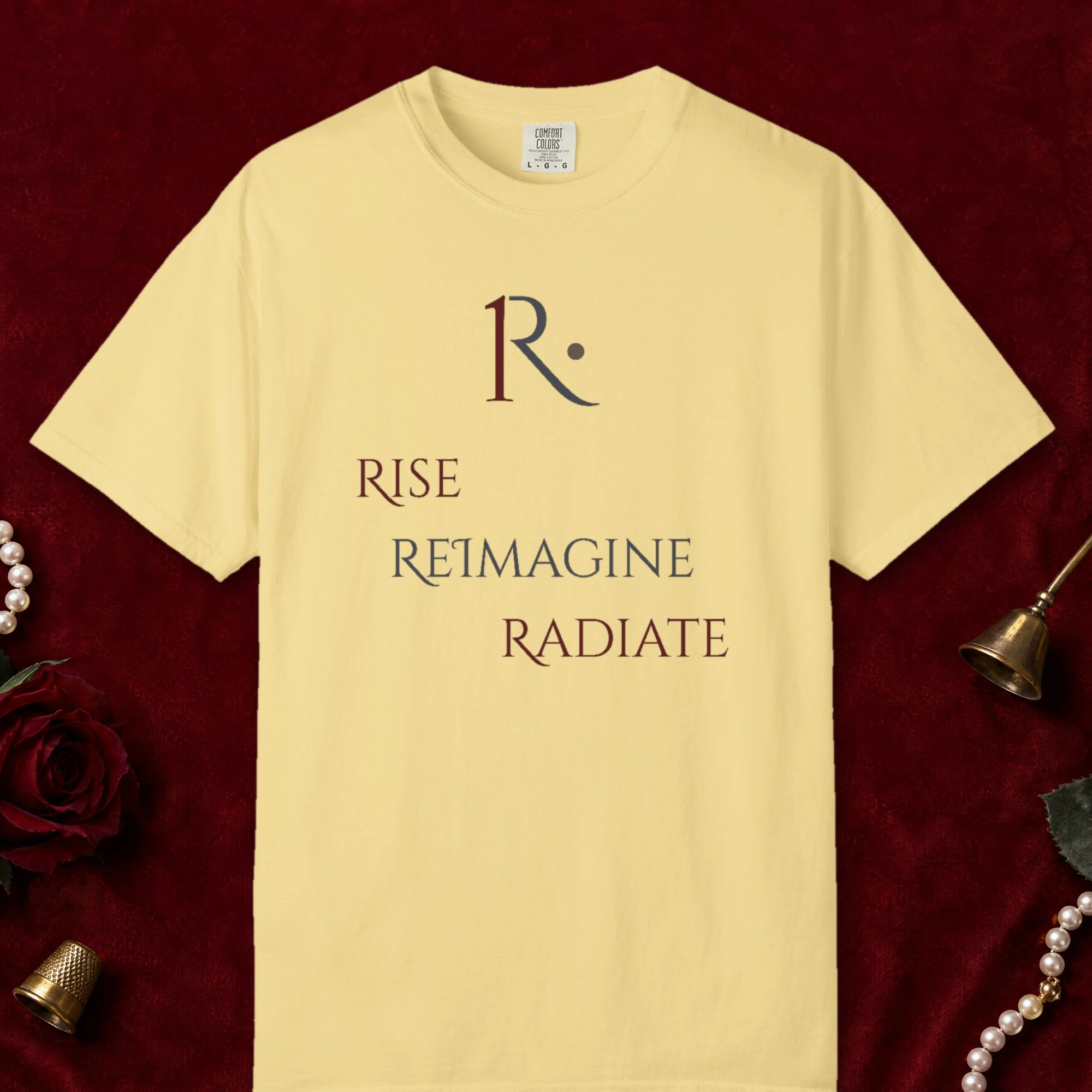 Rise Reimagine Radiate Stacked design on a Butter Comfort Colors 1717 tee, laid flat