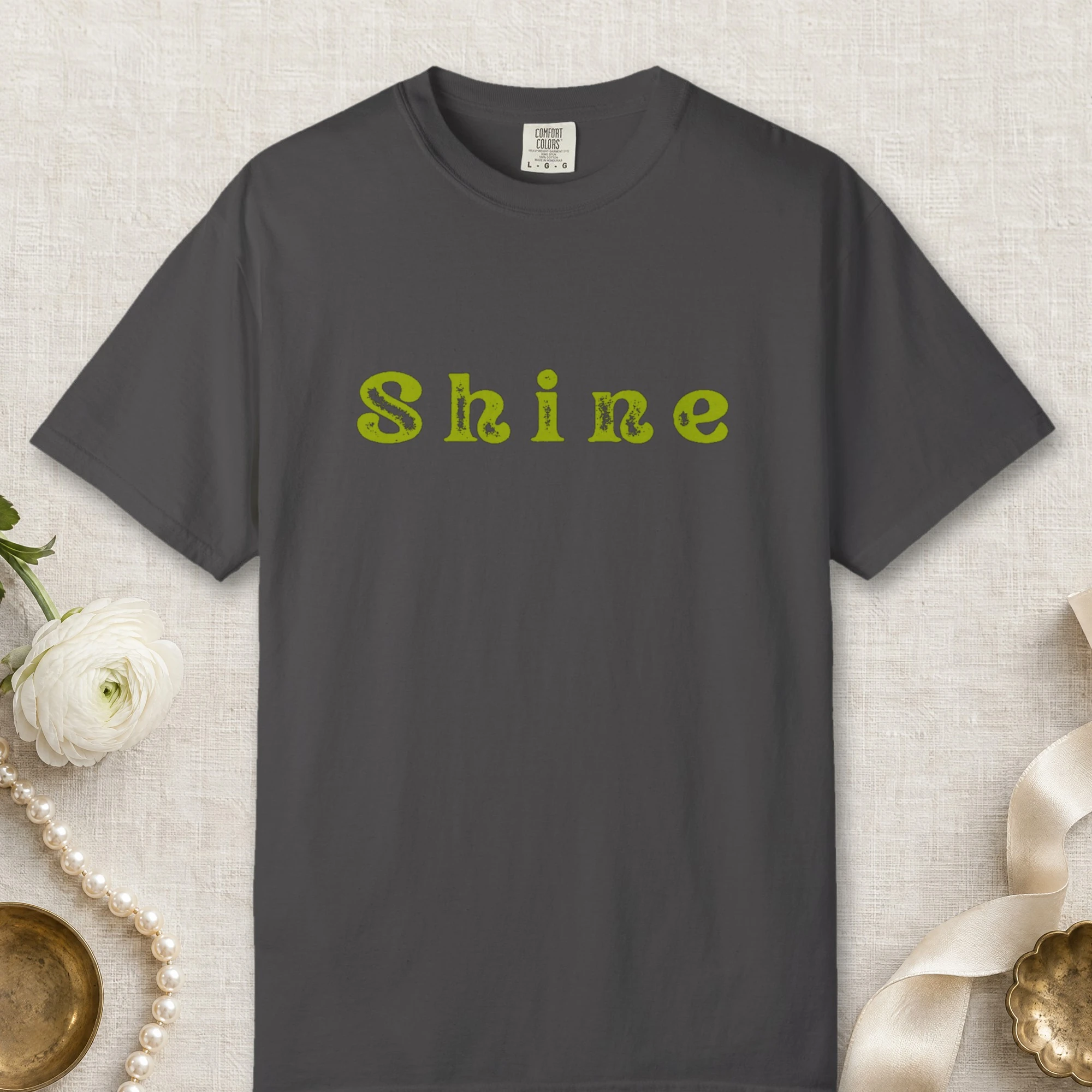 Shine design on a Graphite Comfort Colors 1717 tee, laid flat
