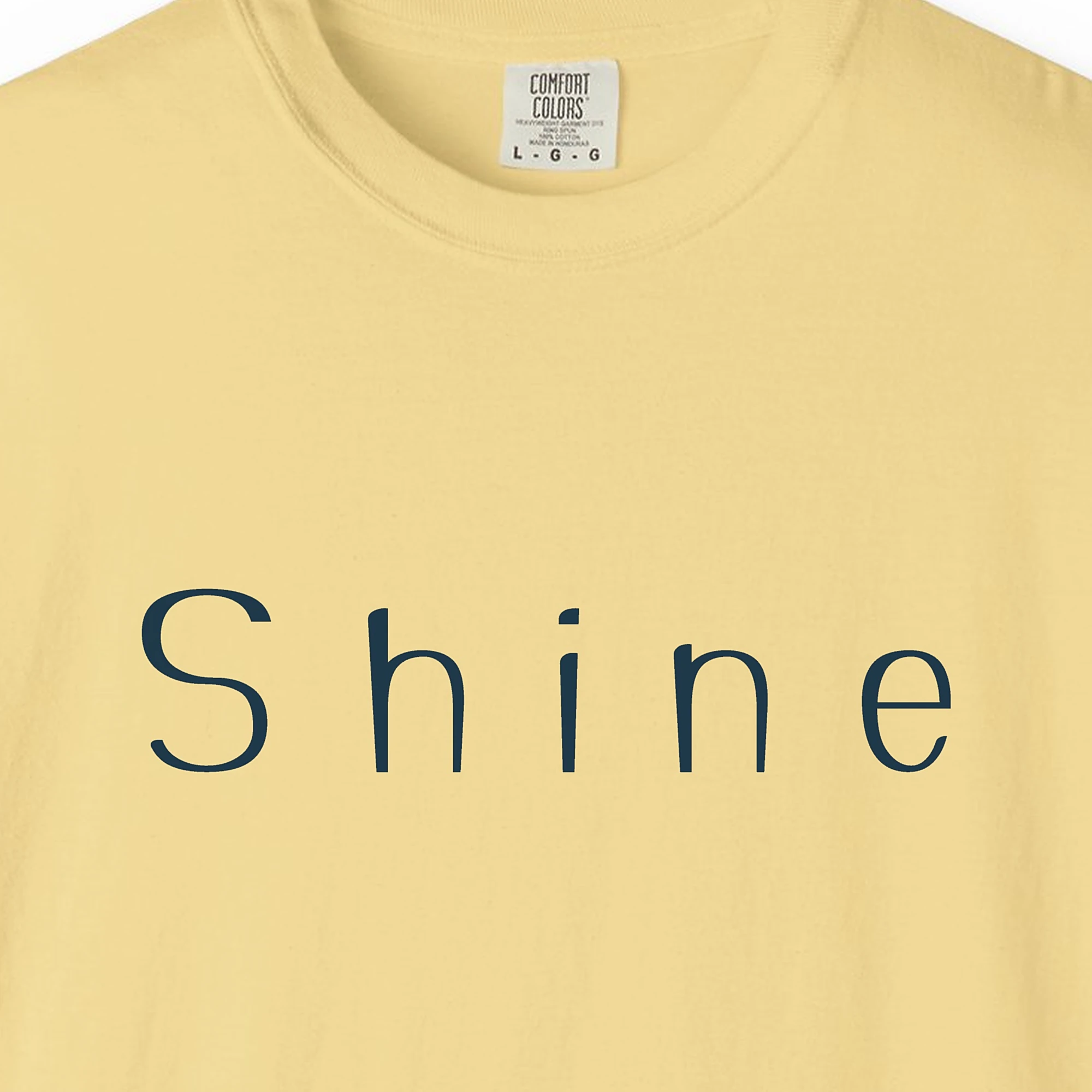 Close-up of the Shine Wide Letter print on a Butter Comfort Colors 1717 tee