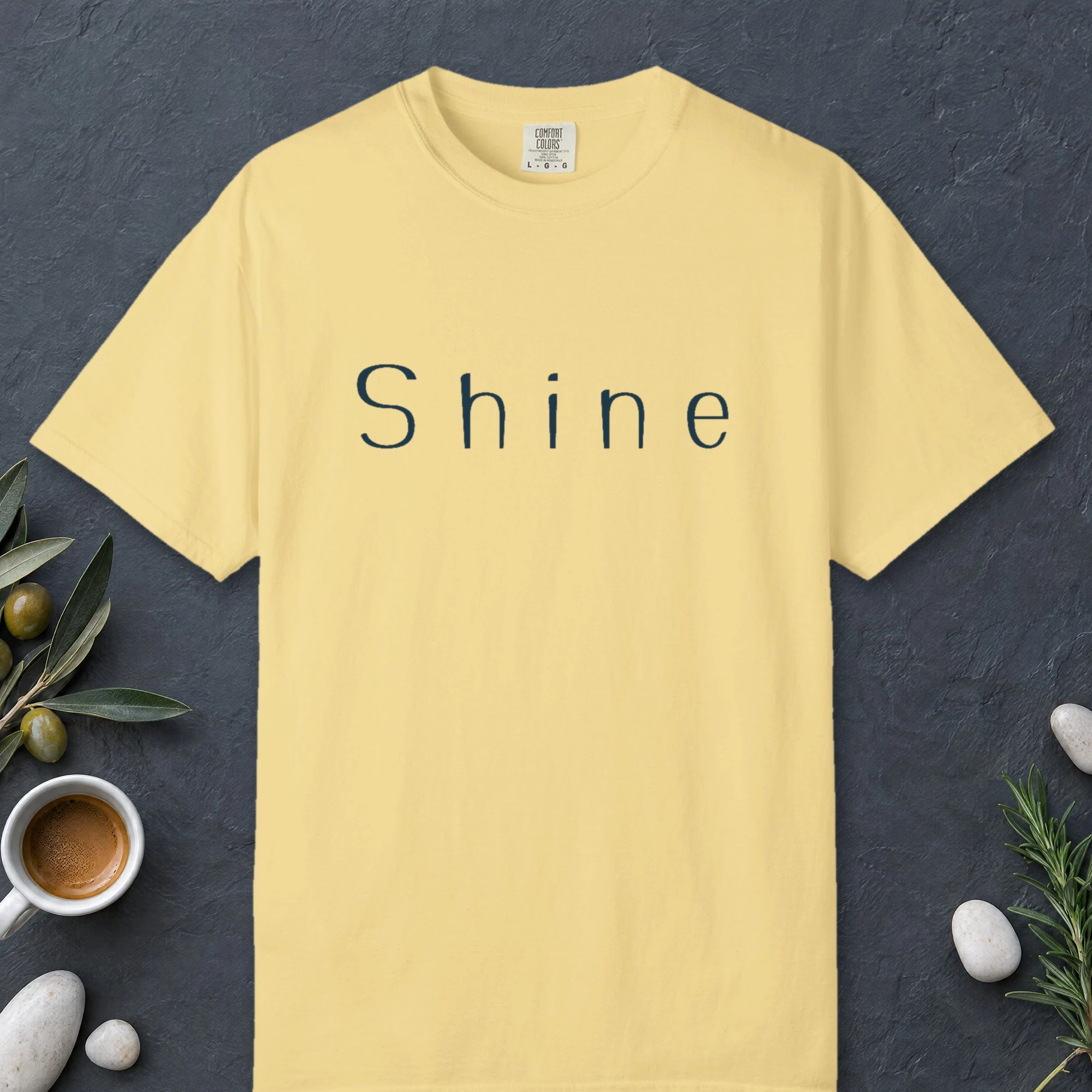 Shine Wide Letter design on a Butter Comfort Colors 1717 tee, laid flat