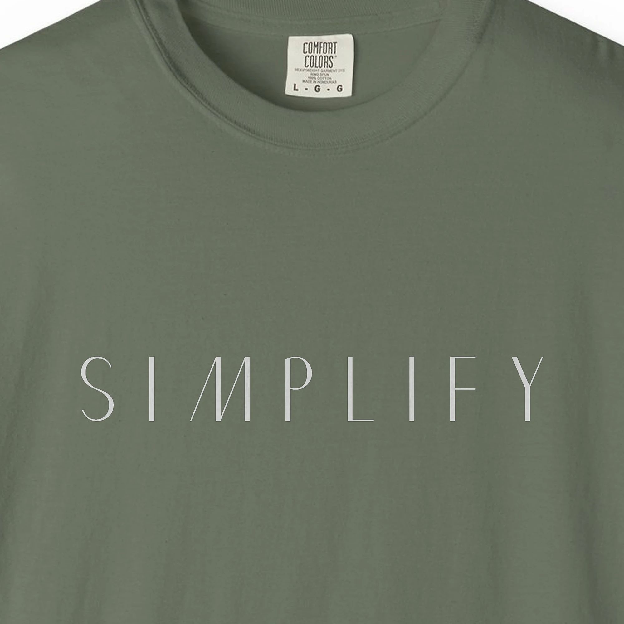 Close-up of the Simplify Spaced Capitals print on a Moss Comfort Colors 1717 tee