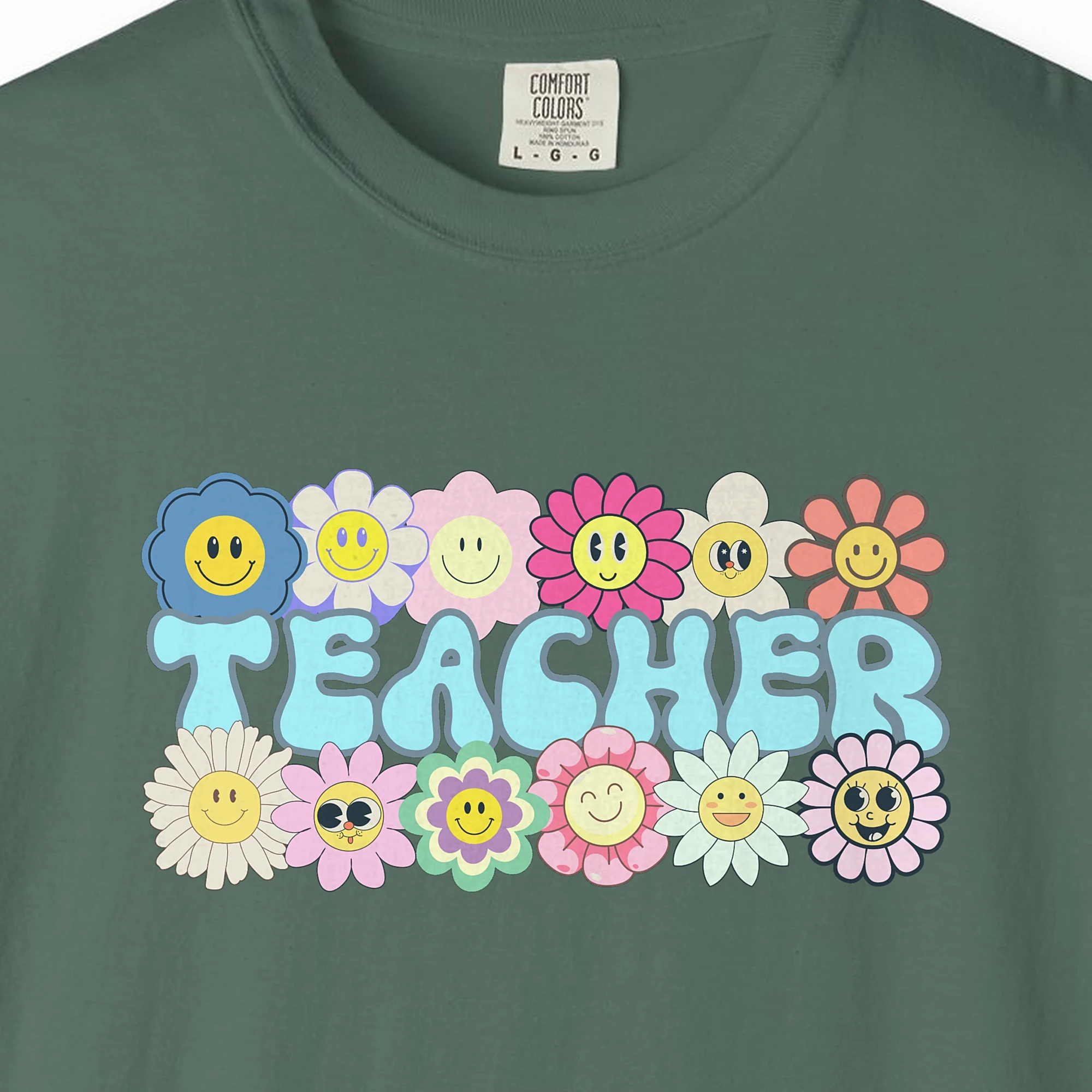 Close-up of the Smiling Daisies Teacher print on a Blue Spruce Comfort Colors 1717 tee