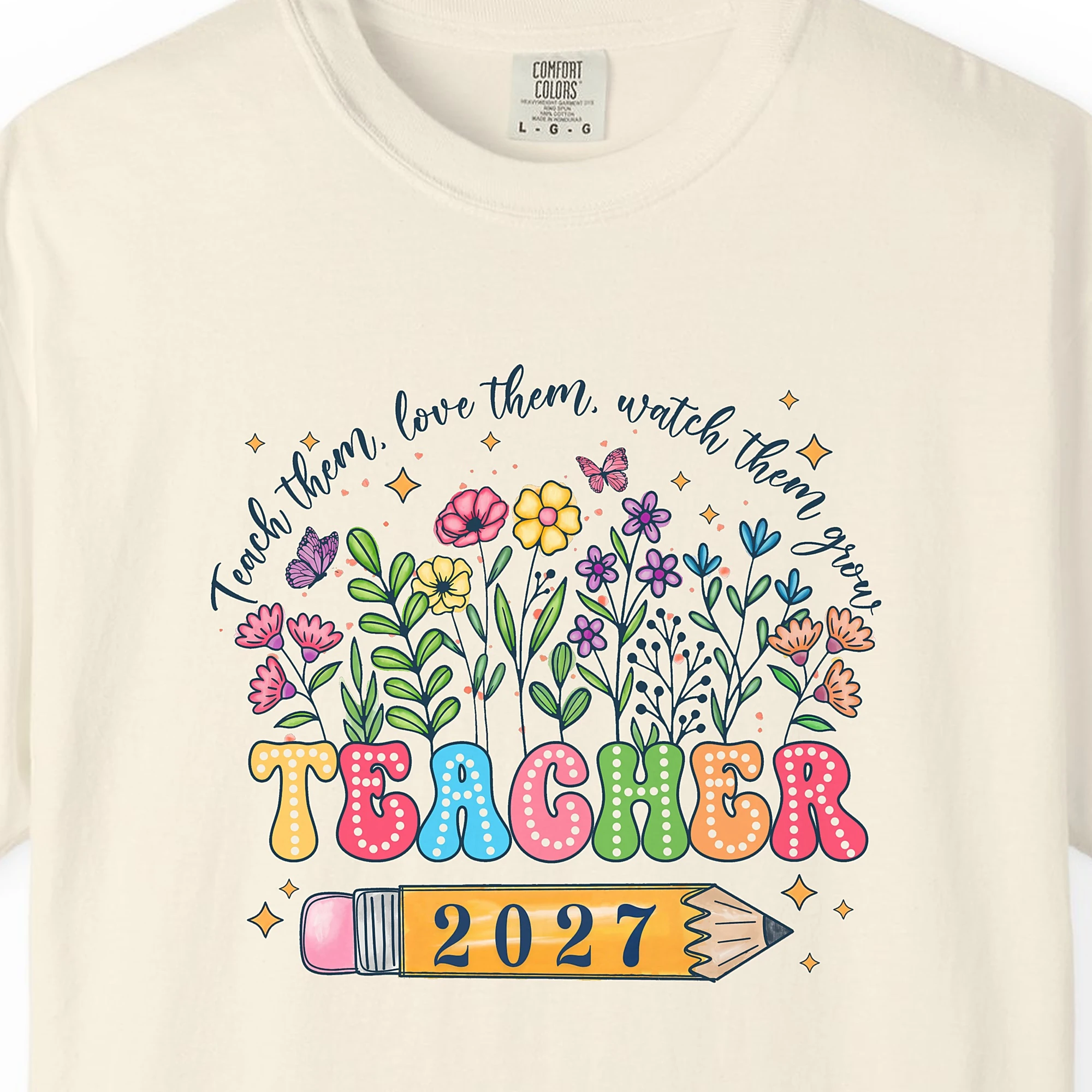 Close-up of the Teach Them Love Them print on a Ivory Comfort Colors 1717 tee
