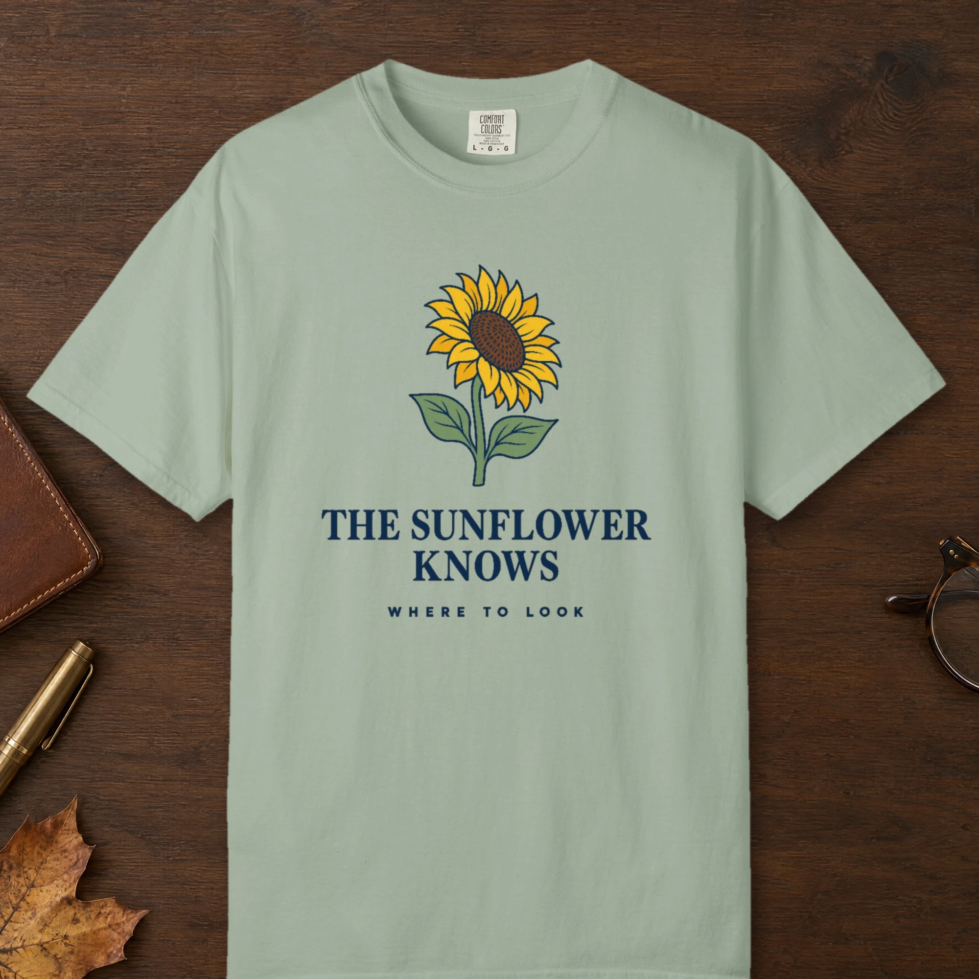 The Sunflower Knows design on a Bay Comfort Colors 1717 tee, laid flat