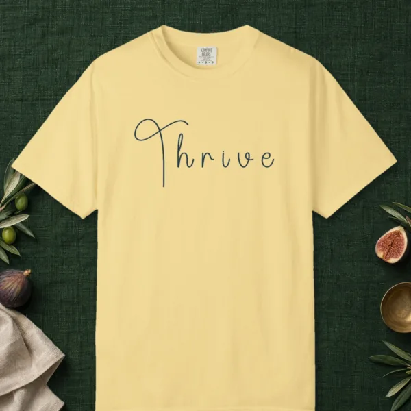 Thrive Handwritten design on a Butter Comfort Colors 1717 tee, laid flat