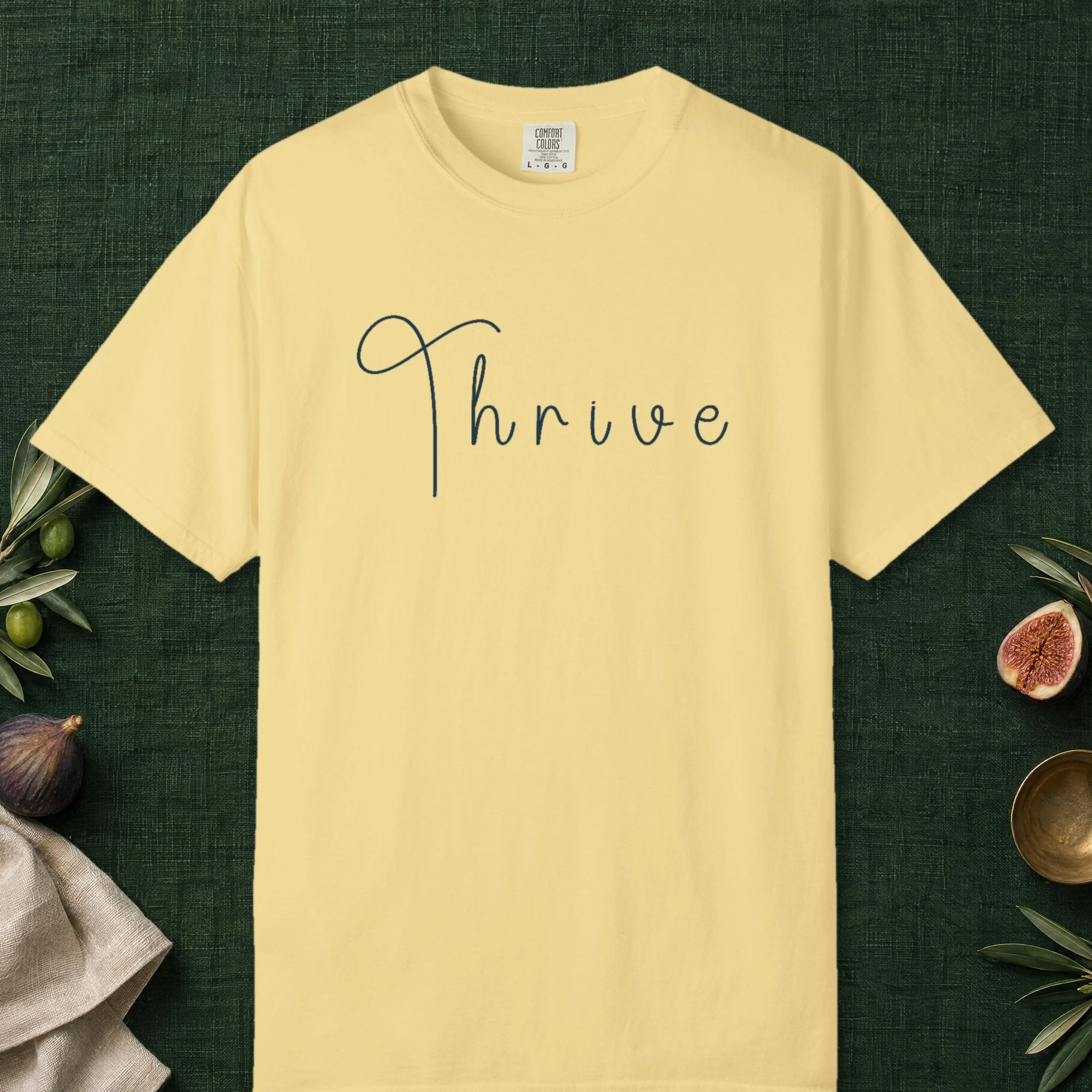 Thrive Handwritten design on a Butter Comfort Colors 1717 tee, laid flat